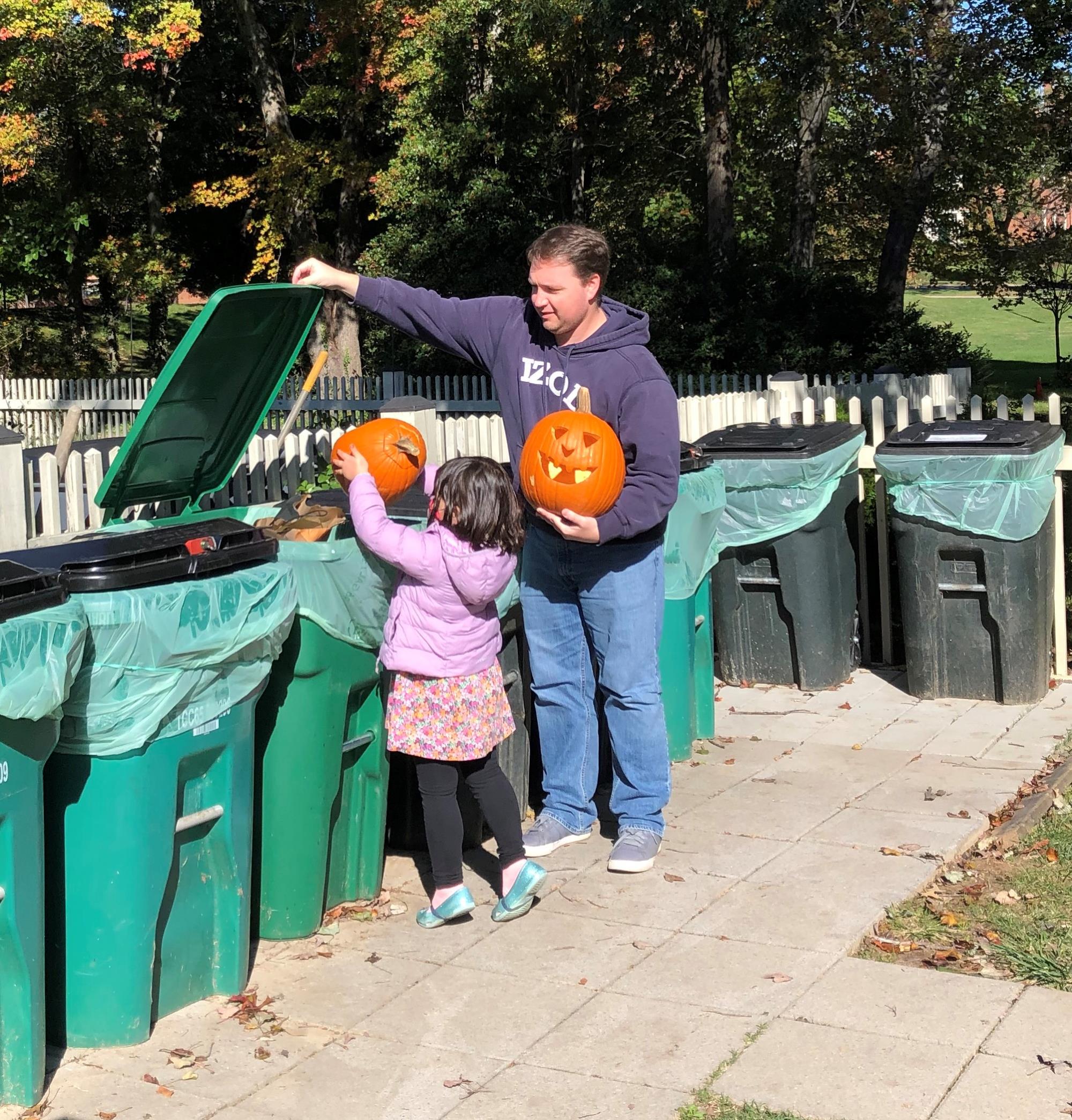 father and daughter composting pumpkins