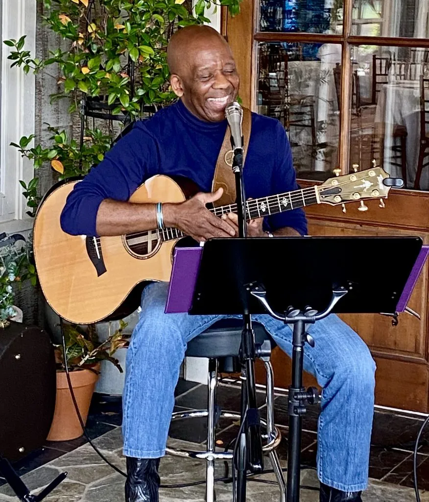 Musician Calvin Earl seated with his guitar, microphone, and music stand